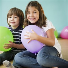 Hispanic brother and sister holding balloons
