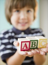 Hispanic boy holding alphabet blocks