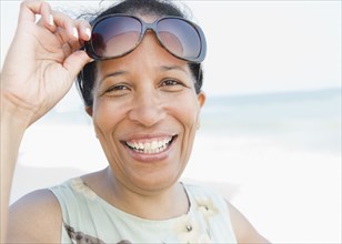 Smiling Black woman wearing sunglasses on beach
