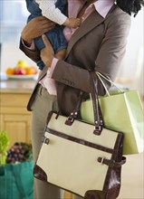 Mixed race mother holding baby and carrying bags