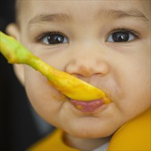Mixed race baby eating from spoon