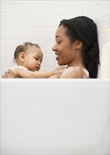 Mixed race woman bathing with baby