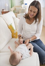 Mother changing baby's diaper on sofa