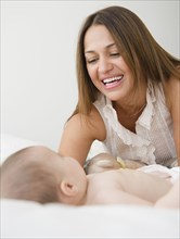 Mother smiling at baby on bed