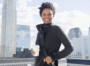 Black woman drinking coffee on rooftop