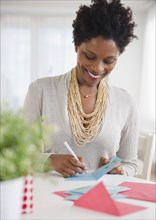 Black woman writing on birthday card
