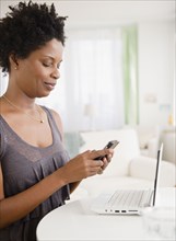 Black woman text messaging on cell phone