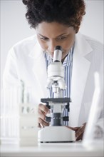 Black scientist looking into microscope
