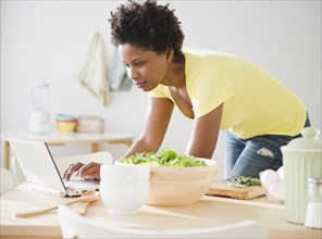 Black woman using laptop on dining room table