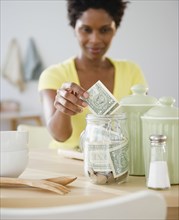 Black woman putting money in jar