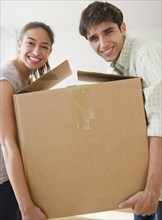 Couple carrying cardboard box together