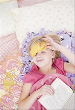 Caucasian girl in sleep mask reading book