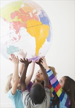 Children lifting up plastic globe