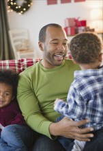 Black father and children relaxing on sofa
