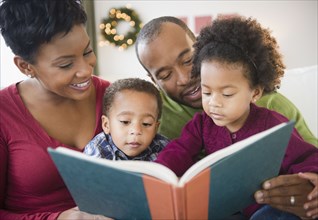 Black family reading book together