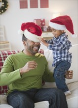Black boy putting Santa hat on his father