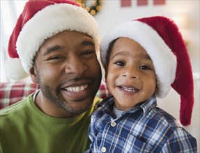 Black father and son wearing Santa hats