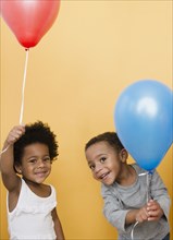 Black children holding helium balloons