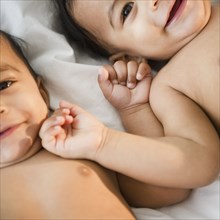 Smiling mixed race twins laying together