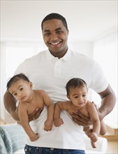 Smiling father holding twin baby boys