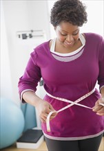 African American woman measuring her waist