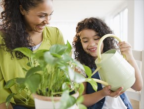 Mother and daughter watering plant together
