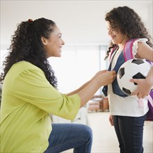 Mother dressing daughter holding soccer ball
