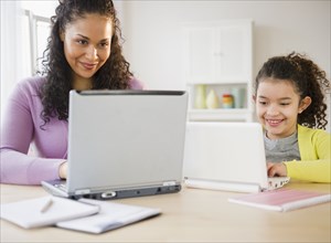Mother and daughter using laptops together