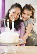 Mother and daughter standing with birthday cake