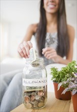 Hispanic teenager putting money into allowance jar