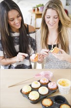 Teenage girls icing cupcakes together