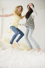 Teenage girls jumping on bed together