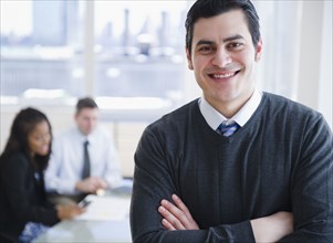 smiling Hispanic businessman with arms crossed