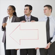 Business people holding whiteboard with arrow