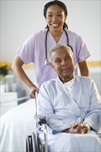 Nurse pushing woman sitting in wheelchair in hospital