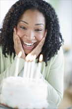 Mixed race woman looking at birthday cake
