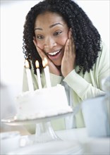 Mixed race woman looking at birthday cake