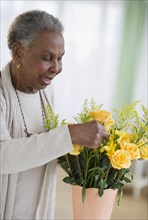 Black woman arranging roses in vase