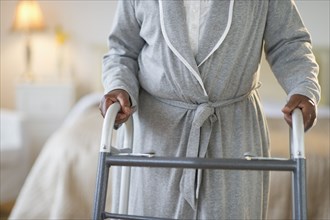 Black woman walking with walker in bedroom
