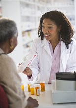 Pharmacist handing medication to woman