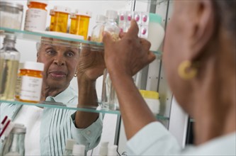 Black woman taking medication from cabinet