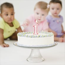 Babies looking at first birthday cake