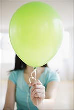 Korean woman holding balloon in front of her face