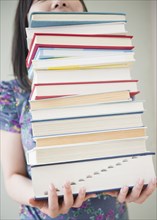 Korean woman holding stack of books