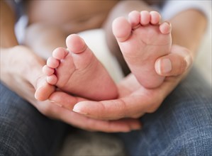 Close up of African American mother holding baby's feet