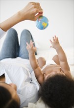 African American mother showing globe to baby boy