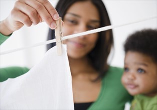African American mother and son hanging clothing on clothes line