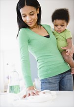 African American mother holding baby boy and cleaning