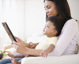 African American mother showing digital tablet to baby boy