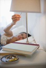 Brazilian woman turning of lamp in bedroom
